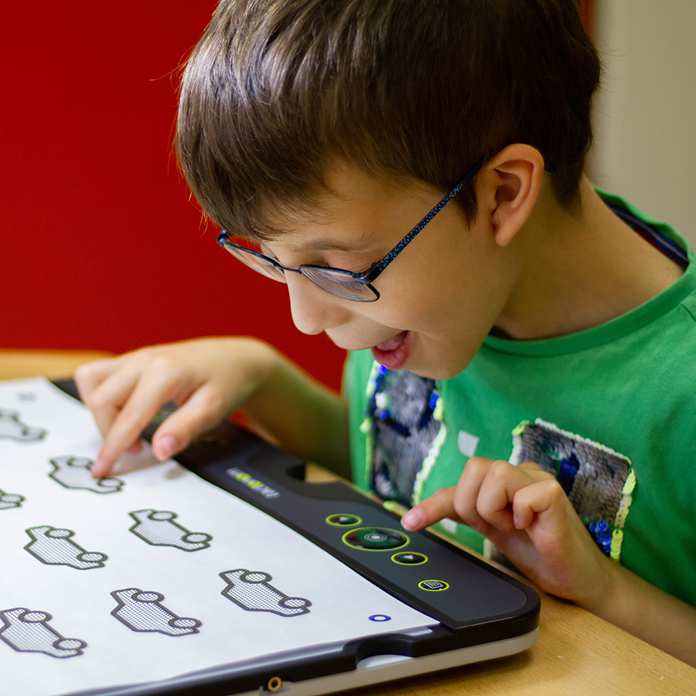 Ein junger Schüler probiert auf dem Reader ein audio-taktiles Auto-Memoryspiel aus.