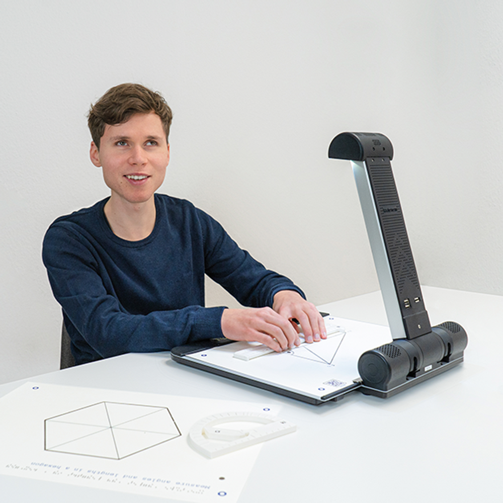 Ein junger Mann sitzt vor dem Tactonom Reader Flex und erkundet damit eine haptische Audiografik.